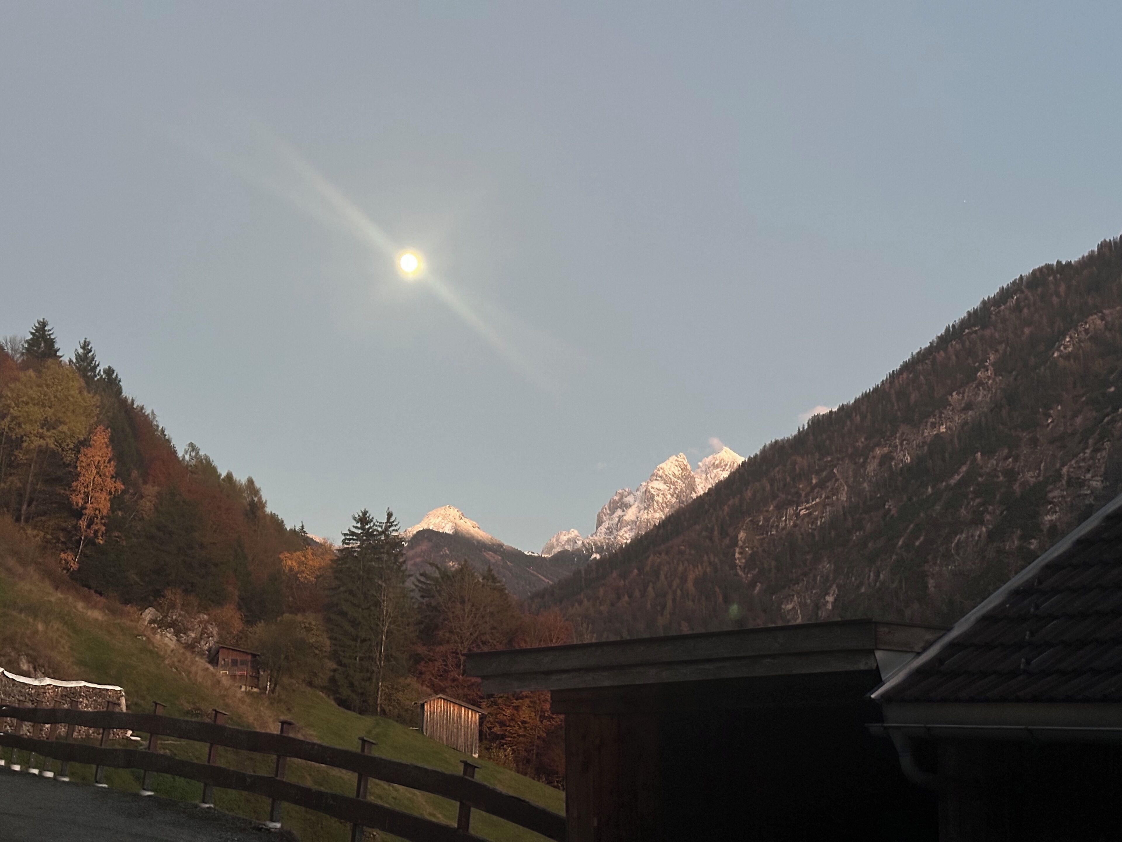 A mountain landscape with a clear sky and a sun shining.