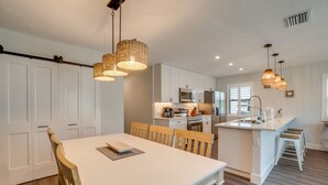Eine moderne Küche mit weißen Schränken, einem Essbereich mit Holzkästen und einer zentralen Kochinsel mit Barhocker.