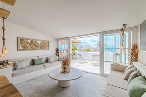 A modern living room with a sofa, a coffee table, and a view of the ocean through large sliding doors. - Casa Vacanze 'Oceania A' with Sea View, Wi-Fi, and Air Conditioning (Chayofa)