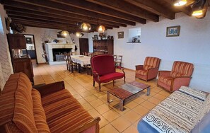 Een woonkamer met een bank, fauteuils, een salontafel en een open haard.