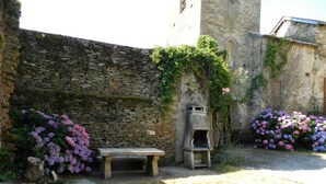 A stone wall with a bench and a small structure, surrounded by flowering plants. - Fraissines at Myriam and Laurent's (FRAISSINES)