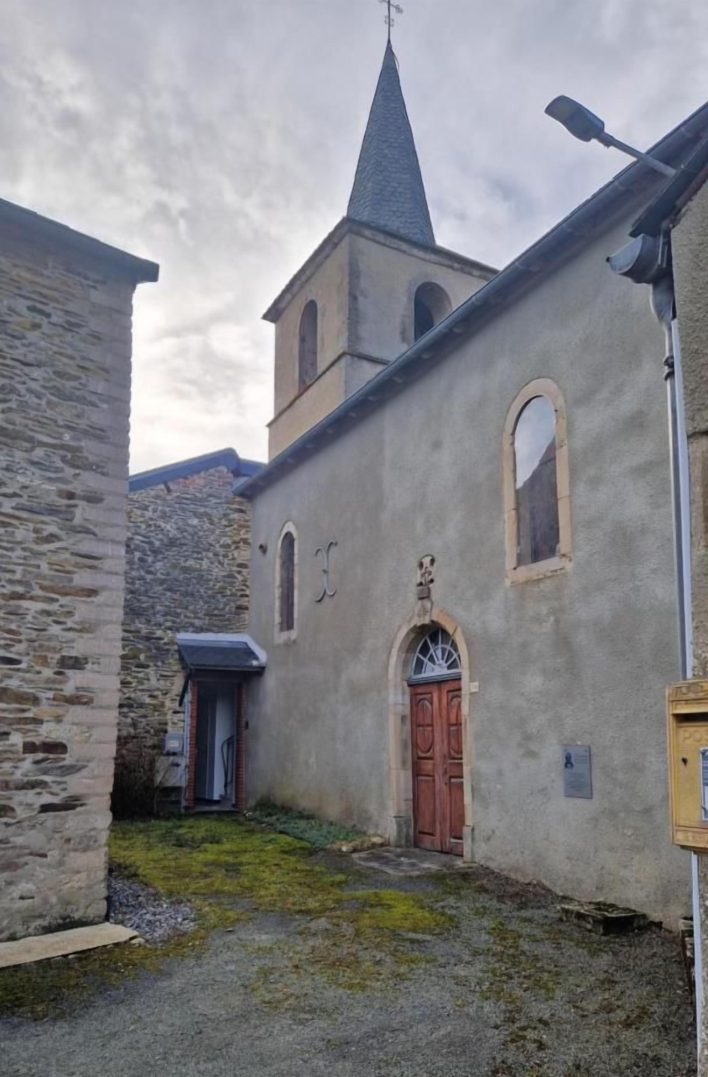 A building with a stone facade, a wooden door, and a small bell tower.