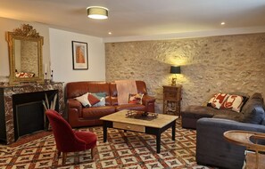 A living room with a fireplace, two sofas, a red armchair, and a patterned floor.