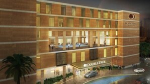 A modern hotel with a prominent "DOUBLETREE" sign, multiple floors, and a pool area.