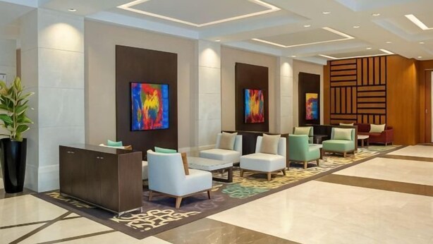 A lobby with a reception desk, seating area, and artwork on the walls.