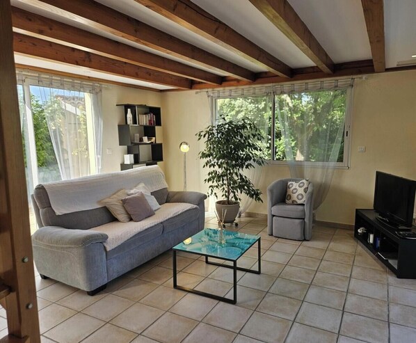 Un salon comprenant un canapé, un fauteuil, une table basse et un téléviseur.