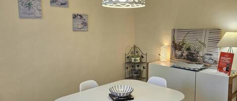 A dining area with a white table, chairs, and a hanging light fixture.