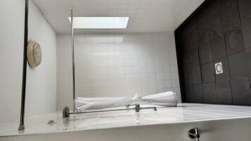 A small, tiled shower room with a white shower curtain rod and a single showerhead.
