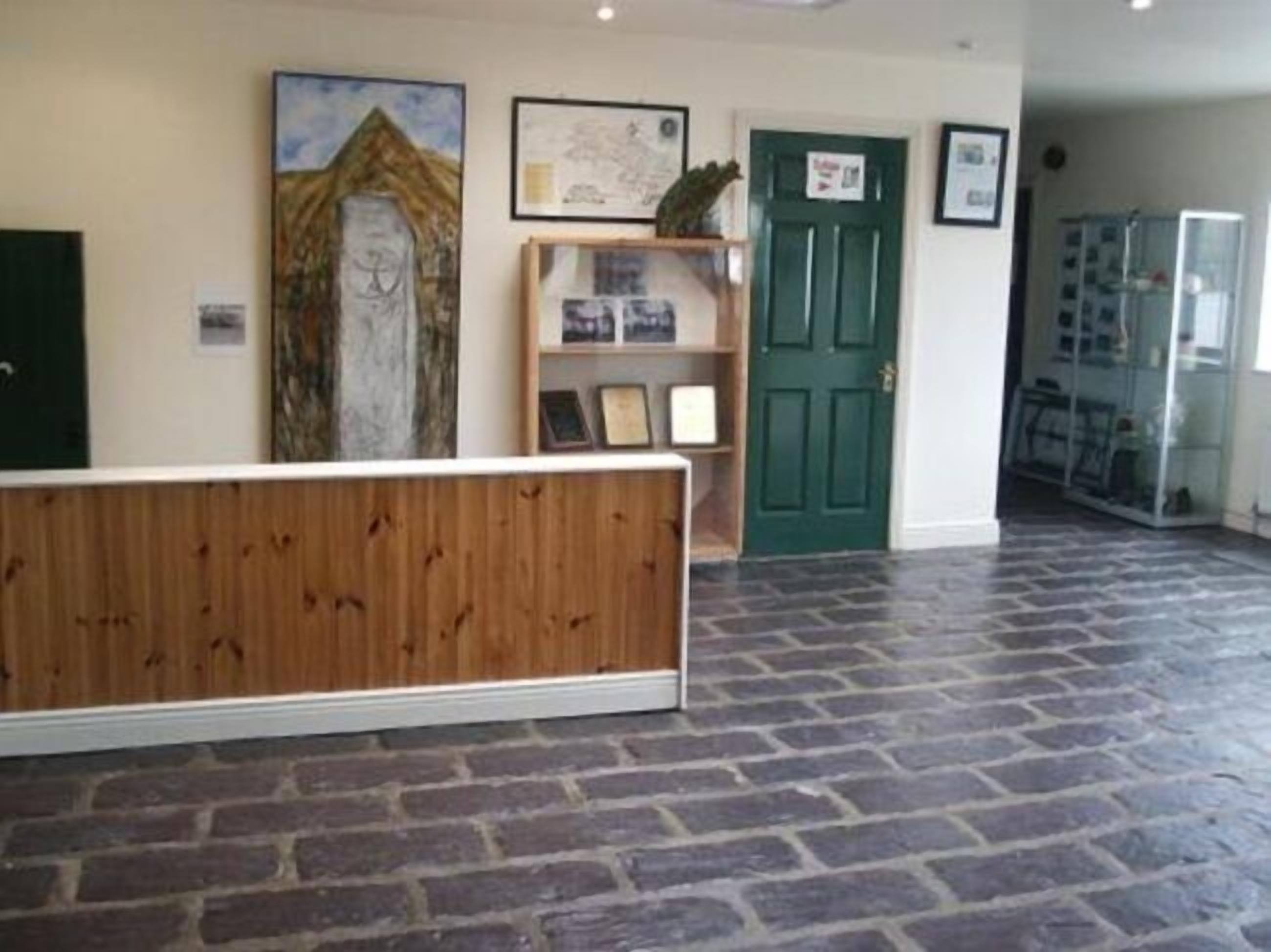 A reception area with a wooden bench, a green door, and framed artwork on the walls.