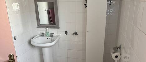 Une salle de bain avec un lavabo blanc, un miroir et des toilettes.
