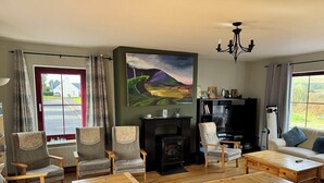 A living room with wooden furniture, a fireplace, and a painting on the wall. - Brú na Dromoda Dromid Hostel (Killeenleagh)