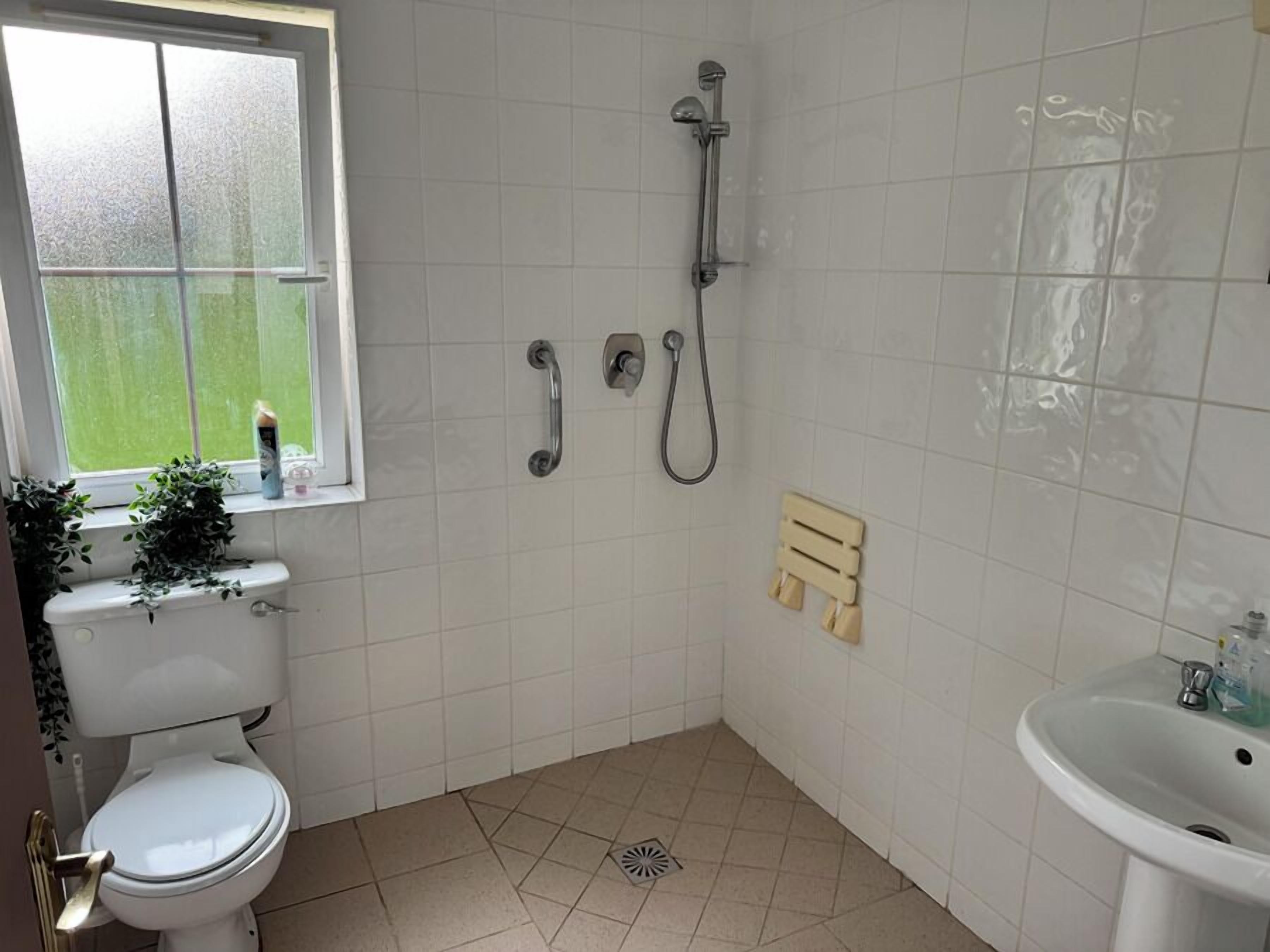 A bathroom with a toilet, a shower, and a sink.