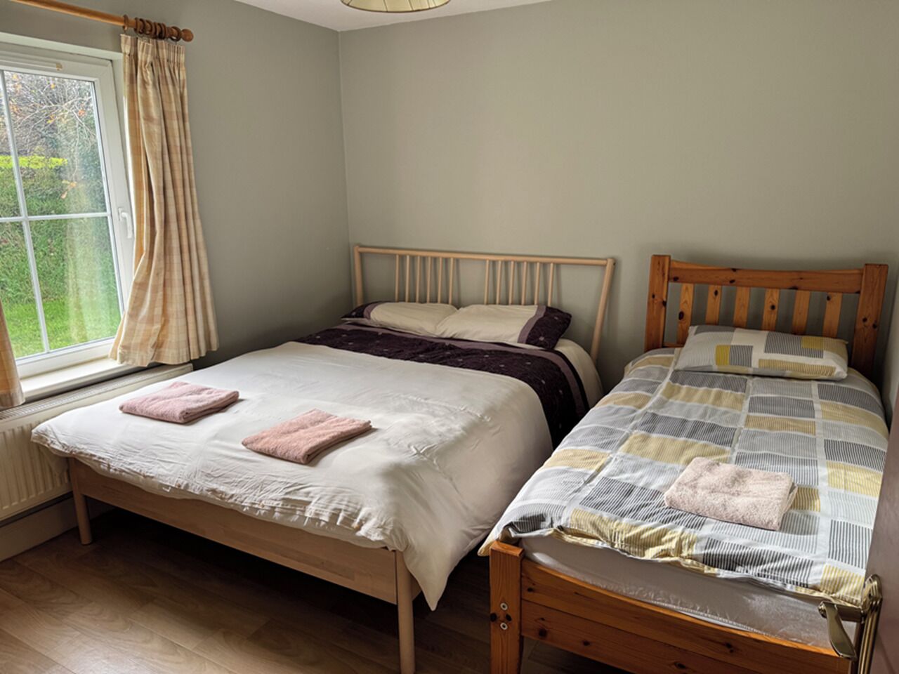 Une chambre à coucher avec deux lits en bois, l’un recouvert d’une couette blanche et marron, et l’autre d’une couette à motifs.