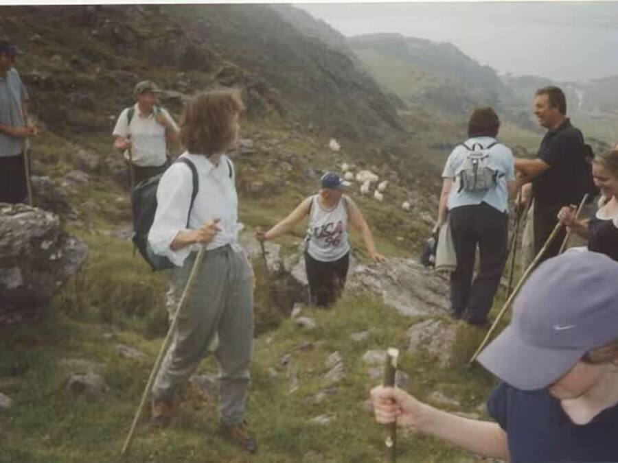 Un grupo de personas caminando por un sendero rocoso en la montaña.
