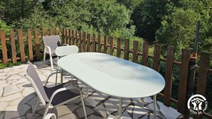 An outdoor patio with a table and chairs, surrounded by a wooden fence and lush greenery. - Aymes - VAOUR - Gîte (VAOUR)