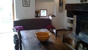A cozy living room with a wooden table, a sofa, and a fireplace. - Aymes - VAOUR - Gîte (VAOUR)