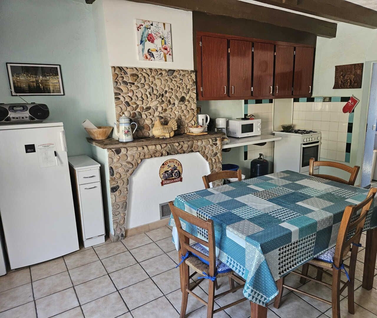 Una cocina compacta con salpicadero de piedra, armarios de madera y una mesa con sillas.