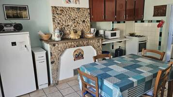 Una cocina compacta con salpicadero de piedra, armarios de madera y una mesa con sillas.
