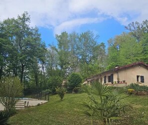 Ein Haus mit Garten, Schwimmbad und blauem Himmel.