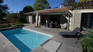 A swimming pool with a wooden deck, outdoor furniture, and a covered patio area with stone walls and tiled roof. - La Montarnaude - PUYCELSI (PUYCELSI)