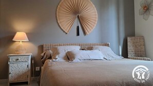 A bedroom with a bed, a nightstand, a lamp, and a wall decoration. - La Montarnaude - PUYCELSI (PUYCELSI)