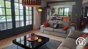 A living room with a sofa, coffee table, and a dining area with chairs and a table. - La Montarnaude - PUYCELSI (PUYCELSI)