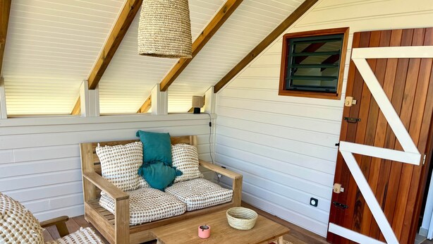A cozy room with a wooden sofa, a small table, and a red rug.