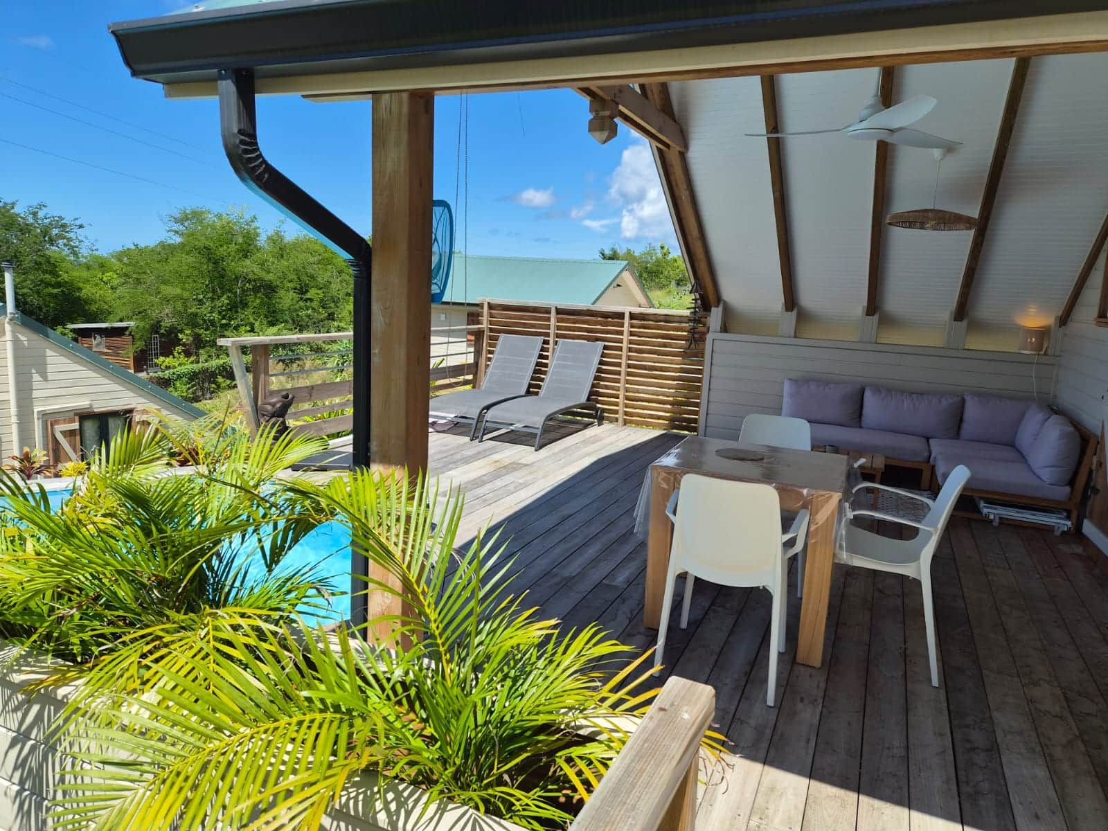 A wooden deck with a pool, lounge chairs, and a sofa.