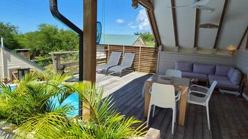 A wooden deck with a pool, lounge chairs, and a sofa.