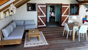 Un acogedor loft con cama en entrepiso, un sofá, una mesa de comedor con sillas y una lámpara colgante.