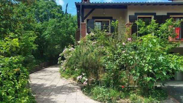 A paved pathway leading to a house with a tiled roof and a brick exterior.