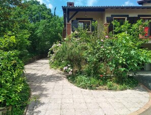 Un chemin pavé mène à une maison avec un toit en tuiles et une façade en briques.