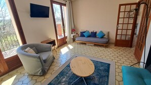 A living room with a sofa, a round wooden table, and a patterned rug.