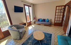 A living room with a sofa, a round wooden table, and a patterned rug.