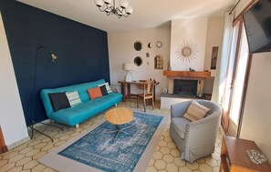 A living room with a blue sofa, a grey armchair, a coffee table, and a fireplace.