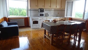 A cozy kitchen with wooden cabinets, a dining table with chairs, and a view of greenery outside.