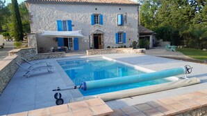 A stone building with a pool, a sun umbrella, and lounge chairs. - Bonnefon - CESTAYROLS (CESTAYROLS)