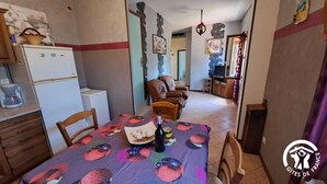 A dining area with a table set for two, a refrigerator, a coffee maker, and a chair. - La Bruninquillé - MONTREDON-LABEISSONNIE (MONTREDON-LABEISSONNIE)