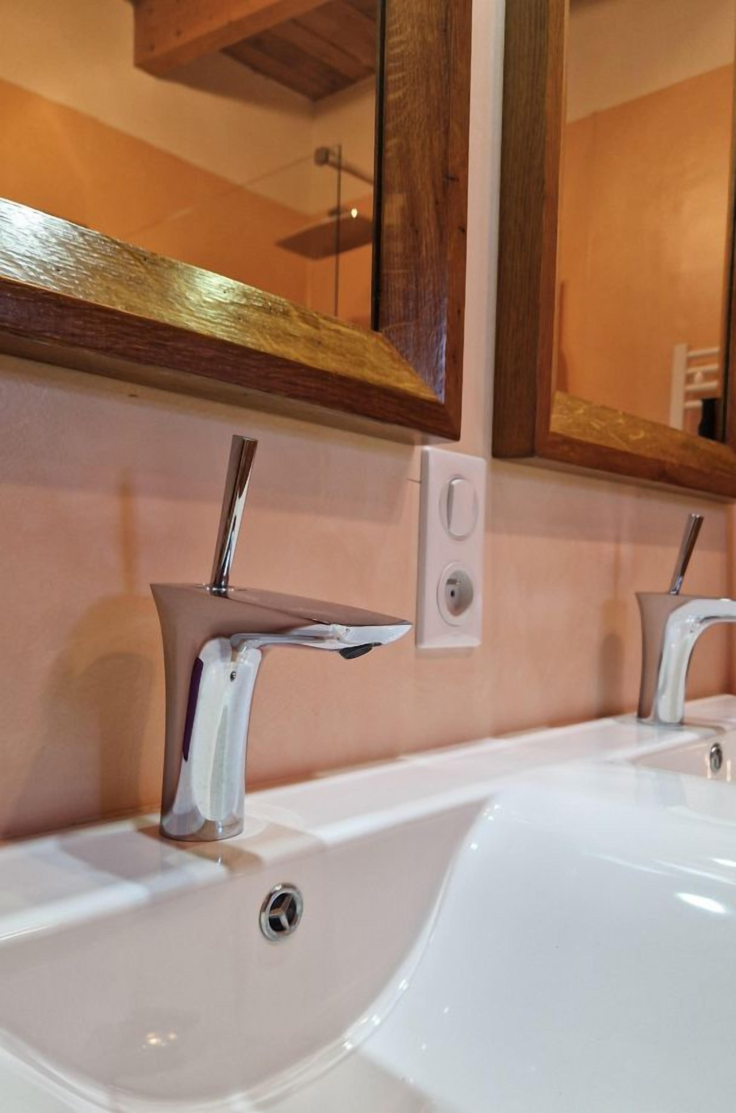 A bathroom with a white sink, two faucets, and a mirror above.