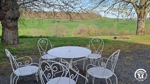 Een ronde metalen tafel met vier stoelen in een natuurlijke buitenomgeving.