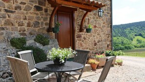 A stone building with a wooden door and a small patio area with a round table and chairs. - Le Petit Serène - VAOUR (VAOUR)