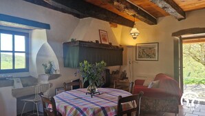 A cozy dining area with a round table covered in a plaid tablecloth, surrounded by wooden chairs. A vase with purple flowers is placed on the table. - Le Petit Serène - VAOUR (VAOUR)