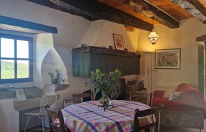 A cozy dining area with a round table covered in a plaid tablecloth, surrounded by wooden chairs. A vase with purple flowers is placed on the table. - Le Petit Serène - VAOUR (VAOUR)