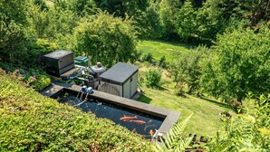 A pond with fish, surrounded by greenery and a small building. - Apartment 'Burkhardt' with Mountain View, Private Terrace and Wi-Fi (Bad Herrenalb)