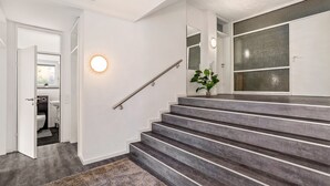 A staircase with a handrail, a round wall light, and a plant. - Apartment 'Burkhardt' with Mountain View, Private Terrace and Wi-Fi (Bad Herrenalb)