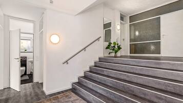 A staircase with a handrail, a round wall light, and a plant.