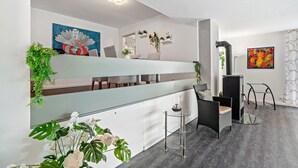 A modern interior with a glass partition, a sofa, a chair, a table, a fireplace, and wall-mounted planters. - Apartment 'Burkhardt' with Mountain View, Private Terrace and Wi-Fi (Bad Herrenalb)