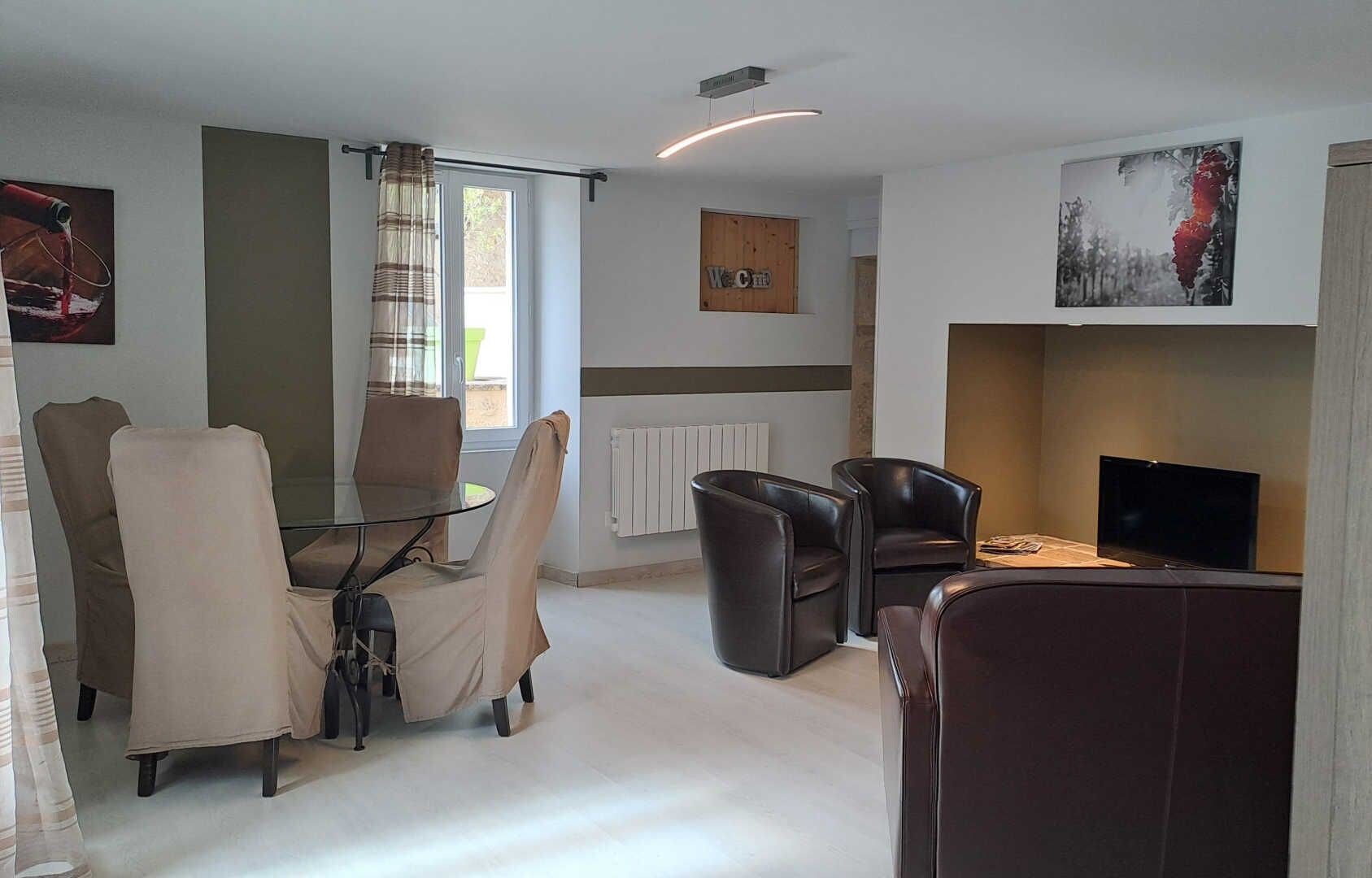 Una sala moderna con una mesa de vidrio, sillones de cuero, chimenea y televisor.