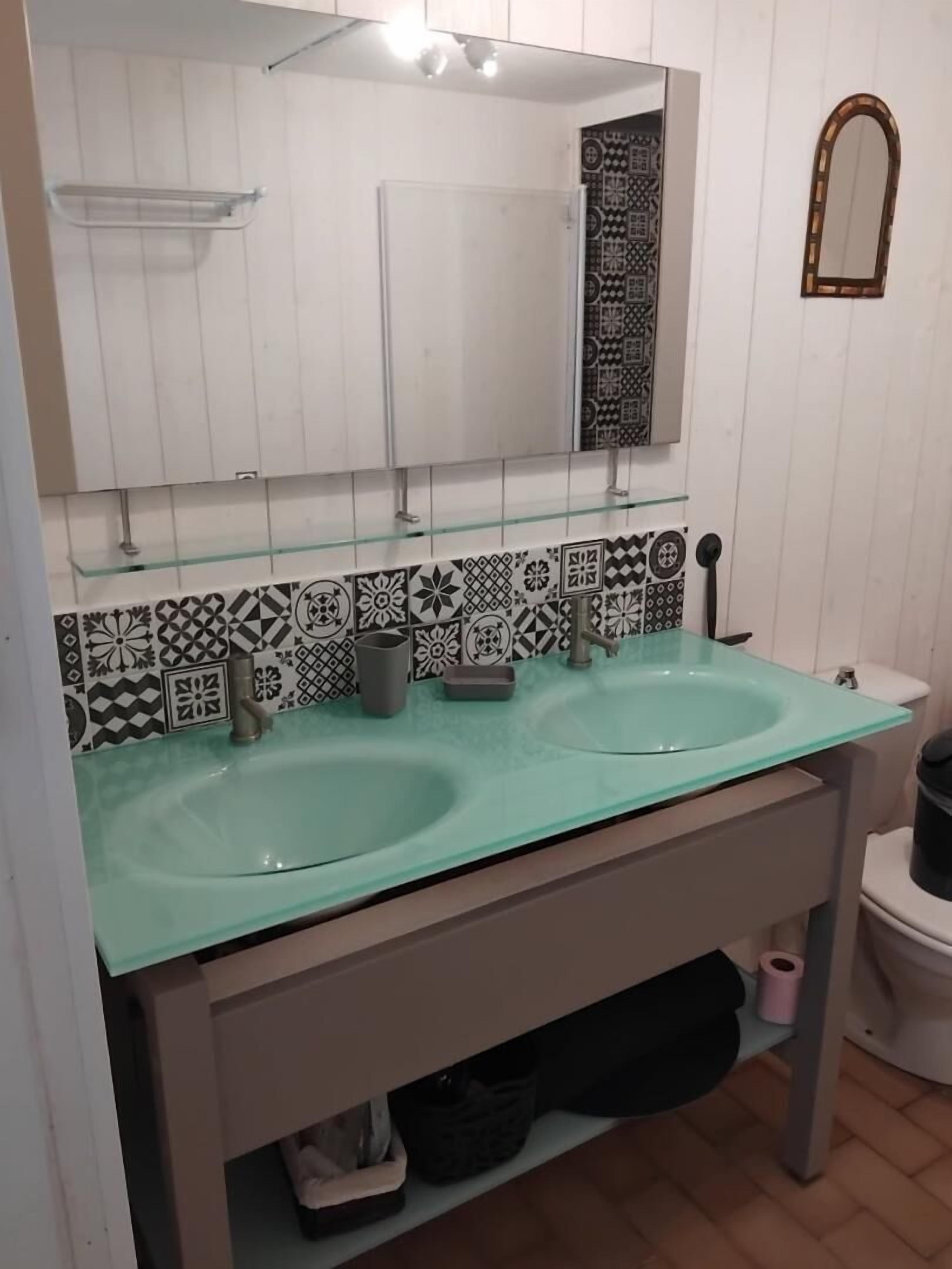 Une salle de bain avec deux lavabos, un miroir et des carreaux décorés.