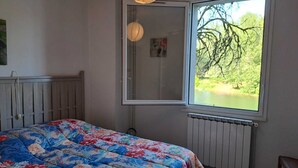 Un dormitorio con cama, ventana, radiador y cabecera de madera.